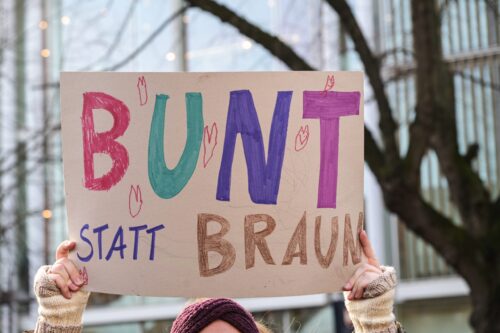 woman-holding-a-cardboard-sign-with-the-german-text-bunt-statt-braun-colorful-instead-of-brown-as-protest-against-racism-and-neo-nazi-fascism-on-a-demonstration-in-lubeck-germany-january-22-2024